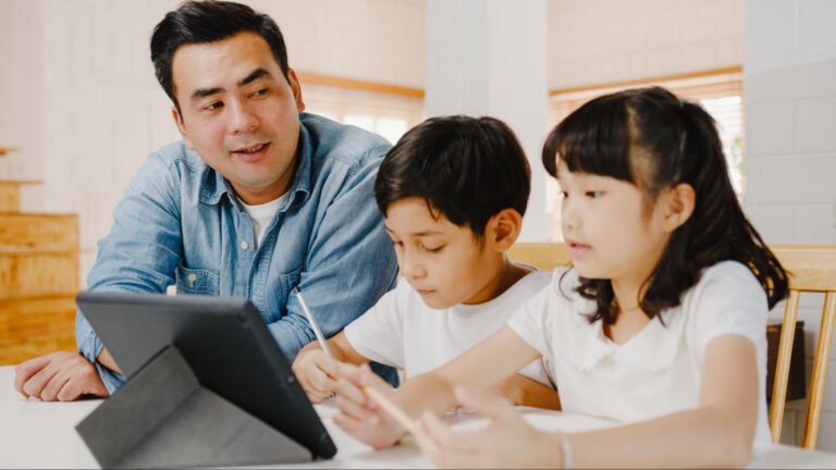A father engages with his children using a tablet, highlighting the importance of parents teaching kids about AI at home.