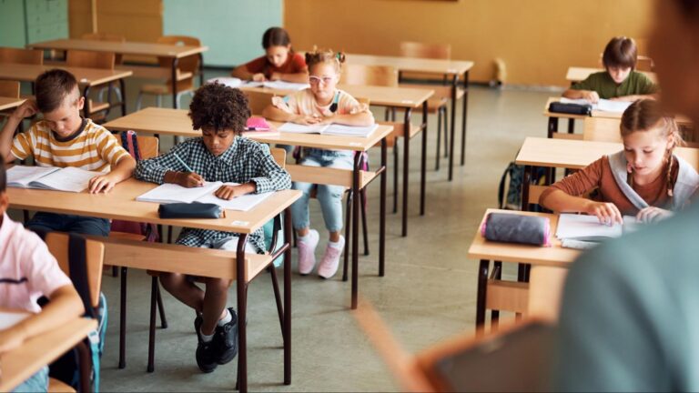 Elementary students focused on writing in a charter school classroom in South Florida, showing an academic learning environment.
