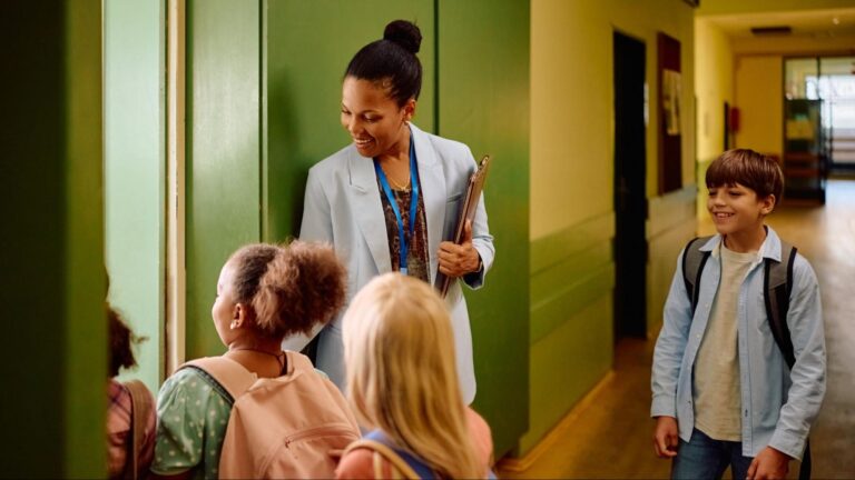 Teacher welcoming students in a Florida school hallway, symbolizing grade placement, academic continuity, and smooth school transfers.