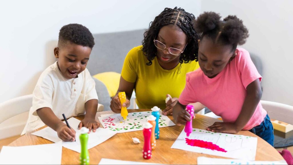 Mother guiding two young children with art projects at home