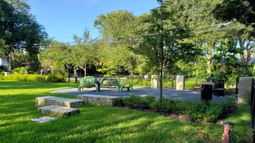 A wide view of a lush green park with mature trees in Coral Gables, perfect for parents balancing career and family life.