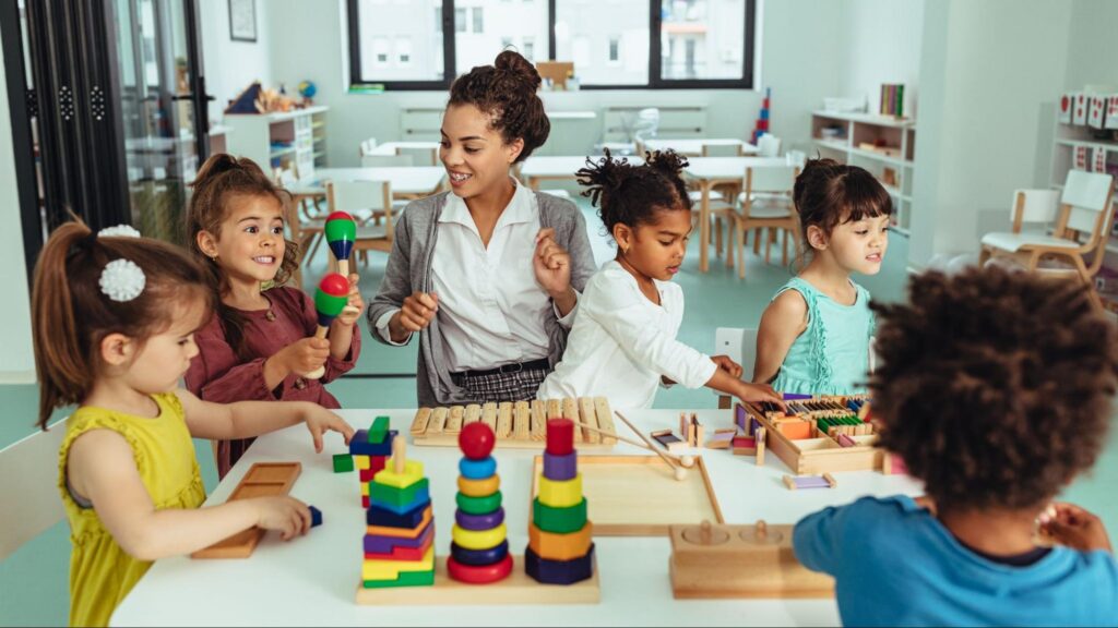 A smiling teacher engaging with a diverse group of toddlers playing with colorful maracas and stacking blocks in a bright preschool classroom, illustrating the importance of early childhood education planning in Miami.