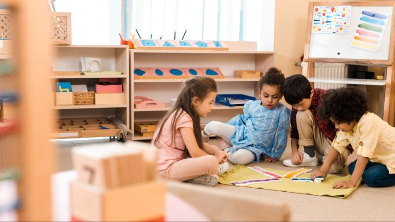 Four young students sitting together on a classroom rug collaborating on a colorful puzzle activity, highlighting the development of social skills and peer collaboration in South Florida educational programs.